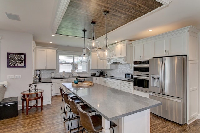 kitchen with hanging light fixtures, tasteful backsplash, a breakfast bar, and appliances with stainless steel finishes