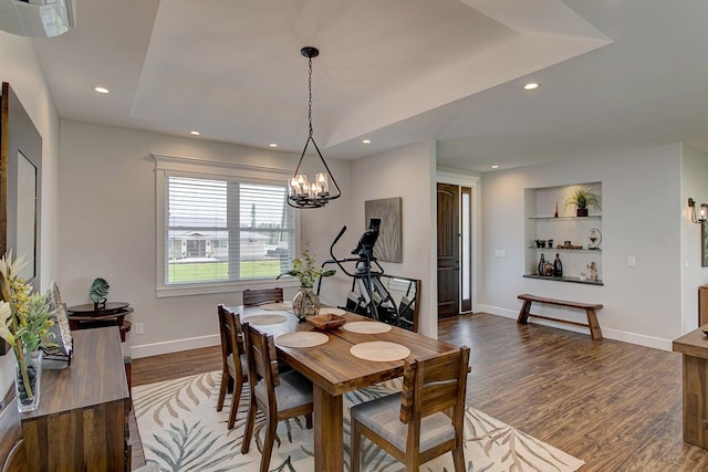 dining area featuring built in shelves, a chandelier, hardwood / wood-style floors, and a raised ceiling