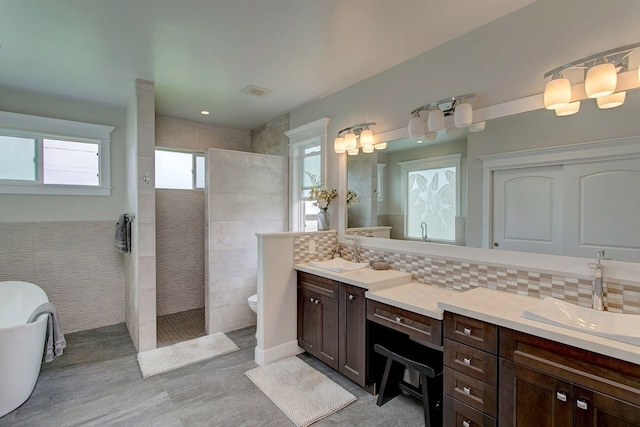 bathroom featuring tile walls, tasteful backsplash, toilet, and dual bowl vanity