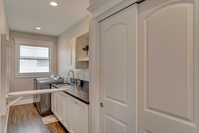 kitchen with washer and dryer, dark hardwood / wood-style flooring, white cabinetry, and sink