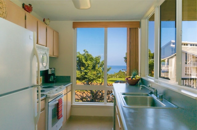 kitchen with a water view, white appliances, light tile floors, light brown cabinets, and sink