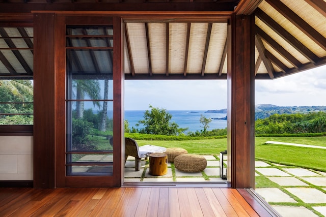 entryway featuring a water view, vaulted ceiling with beams, and wood-type flooring