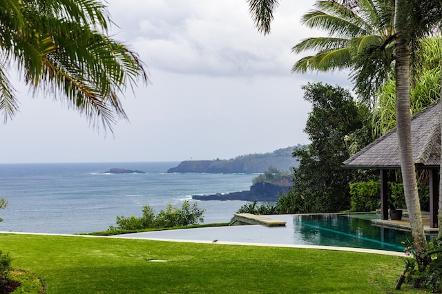 view of swimming pool featuring a yard and a water view