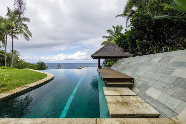 view of swimming pool featuring a lawn and a water view