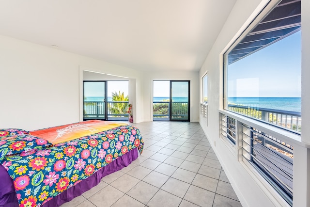 bedroom featuring light tile floors, access to exterior, and a water view