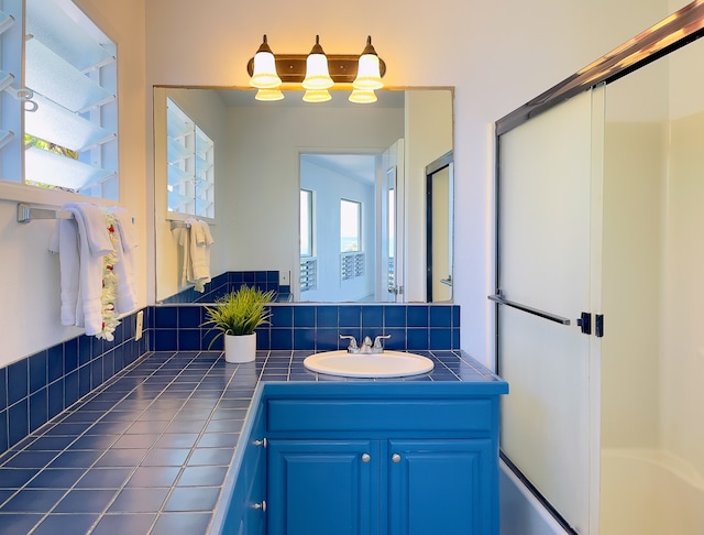 bathroom featuring backsplash, combined bath / shower with glass door, and vanity