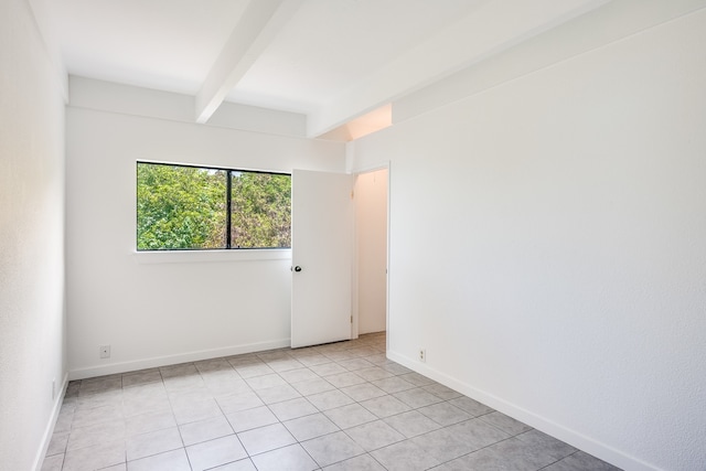 tiled empty room featuring beamed ceiling