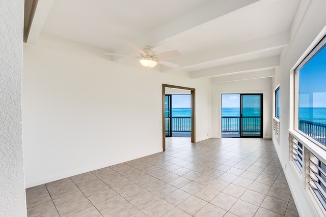 spare room featuring a water view, light tile floors, ceiling fan, and beamed ceiling