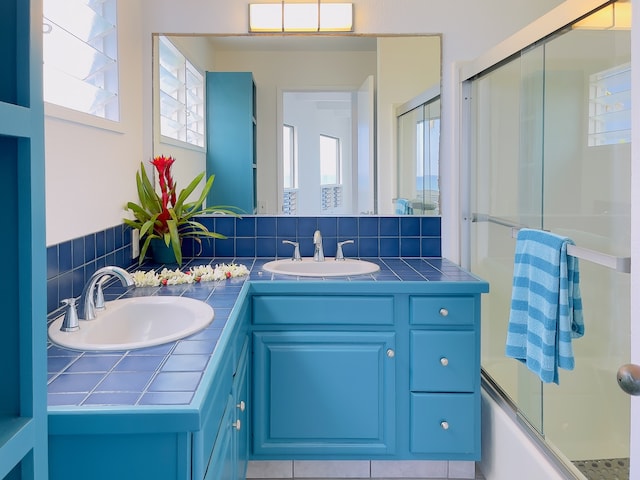 bathroom featuring combined bath / shower with glass door, dual vanity, and tile flooring