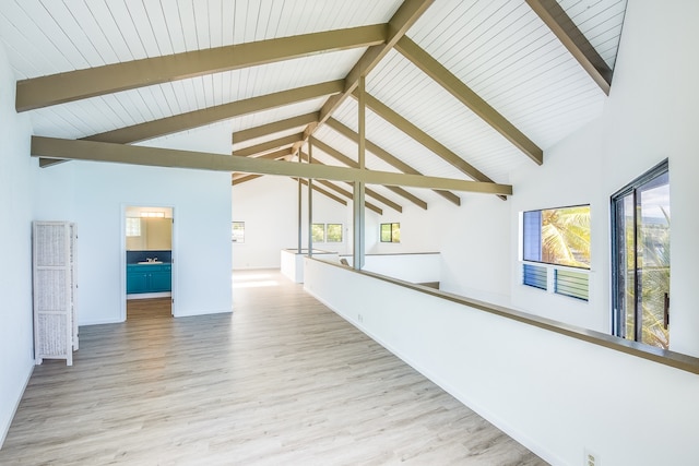 additional living space featuring a healthy amount of sunlight, high vaulted ceiling, light wood-type flooring, and beam ceiling