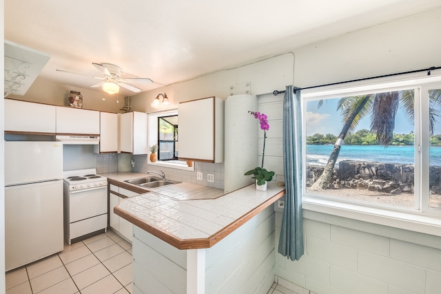 kitchen featuring white appliances, ceiling fan, sink, light tile flooring, and white cabinetry