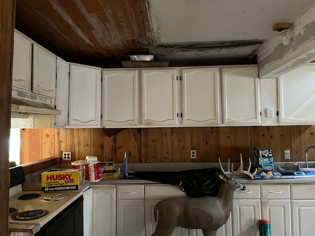 kitchen with white electric stove, white cabinetry, and wooden walls