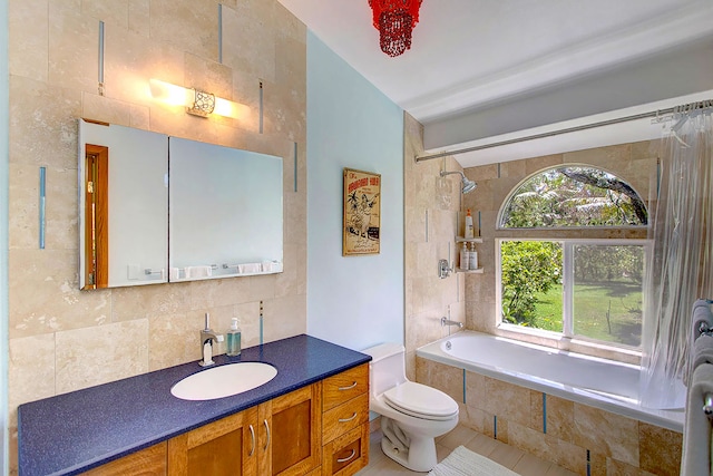 full bathroom with tile walls, toilet, large vanity, and tiled shower / bath