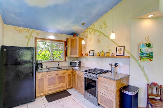 kitchen featuring gas stove, black refrigerator, light tile floors, pendant lighting, and sink