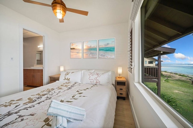 bedroom with a water view, ensuite bathroom, ceiling fan, access to outside, and hardwood / wood-style flooring