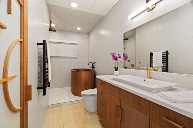 bathroom featuring tile walls, vanity with extensive cabinet space, toilet, and hardwood / wood-style flooring