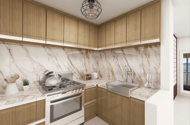 kitchen with tasteful backsplash, light tile flooring, range with gas stovetop, and sink