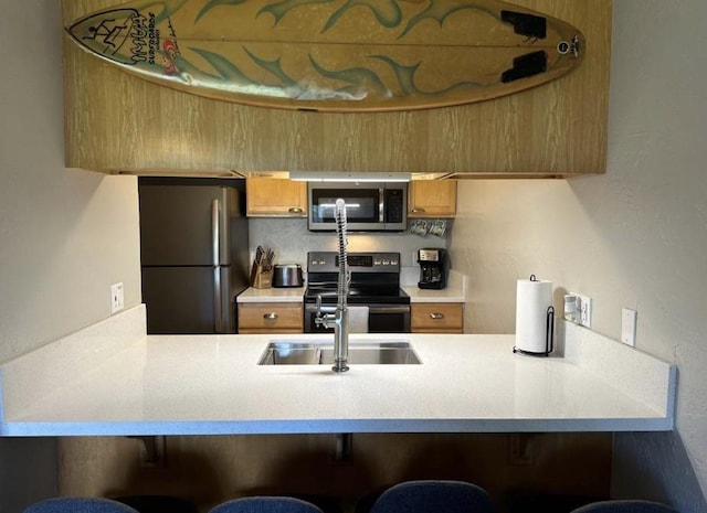 kitchen featuring a kitchen bar, appliances with stainless steel finishes, and sink