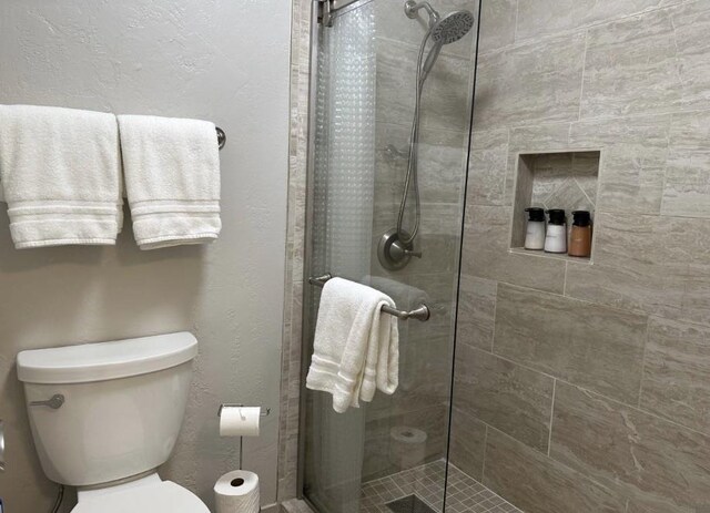 bathroom featuring toilet and a shower with shower door