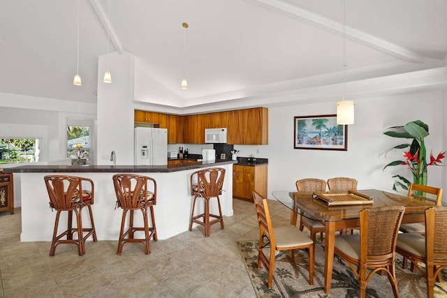 kitchen featuring white appliances, pendant lighting, light tile floors, a breakfast bar, and beam ceiling