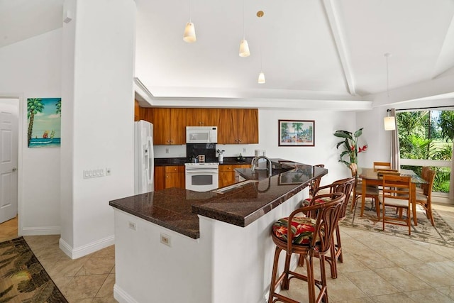 kitchen with a kitchen breakfast bar, light tile floors, decorative light fixtures, white appliances, and lofted ceiling