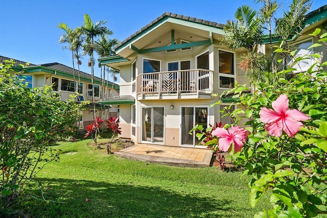 rear view of property with a balcony and a lawn