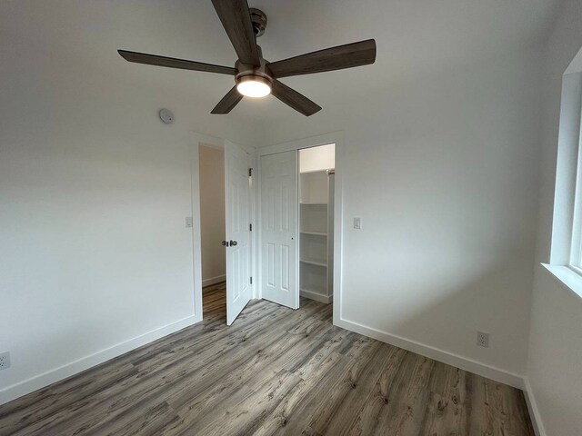 unfurnished bedroom featuring dark hardwood / wood-style flooring, ceiling fan, a closet, and a spacious closet