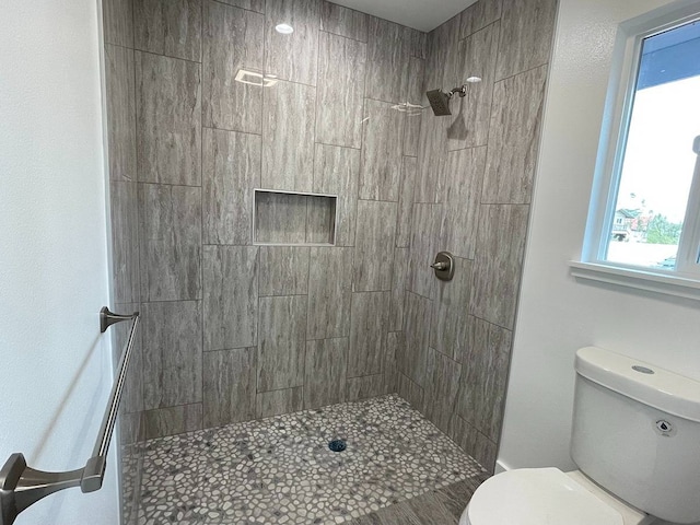 bathroom featuring toilet and a tile shower