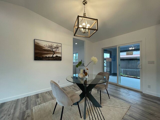 dining room with lofted ceiling, a notable chandelier, and dark hardwood / wood-style floors