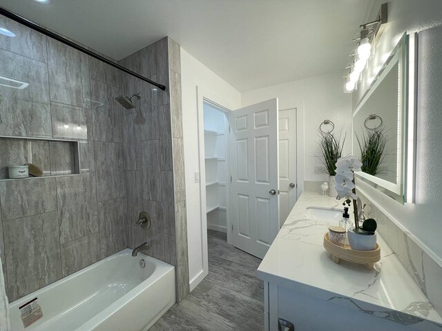 bathroom featuring tiled shower / bath combo, vanity, and wood-type flooring