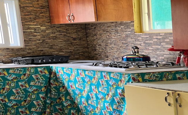 kitchen featuring backsplash, stainless steel gas cooktop, and a healthy amount of sunlight