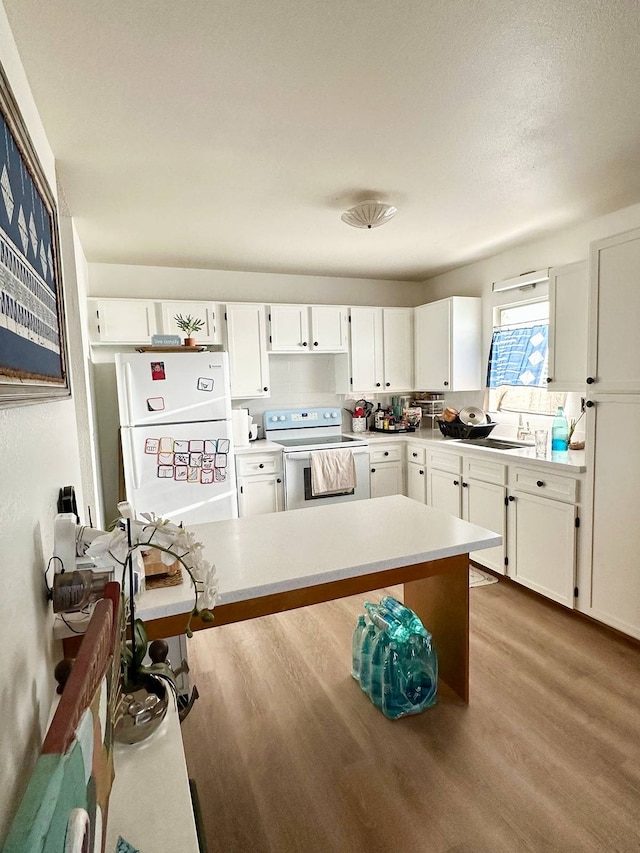 kitchen with white cabinets, light hardwood / wood-style floors, white appliances, and sink