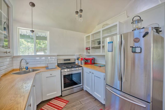 kitchen with white cabinetry, appliances with stainless steel finishes, sink, light wood-type flooring, and tasteful backsplash