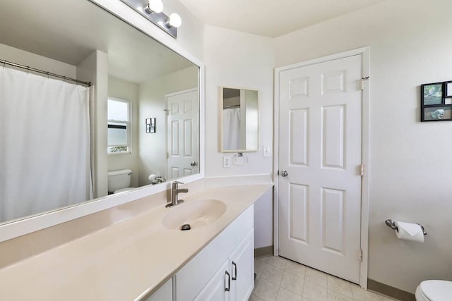 bathroom with toilet, vanity with extensive cabinet space, and tile floors