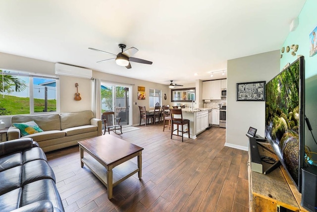 living room featuring an AC wall unit, dark hardwood / wood-style floors, ceiling fan, and sink