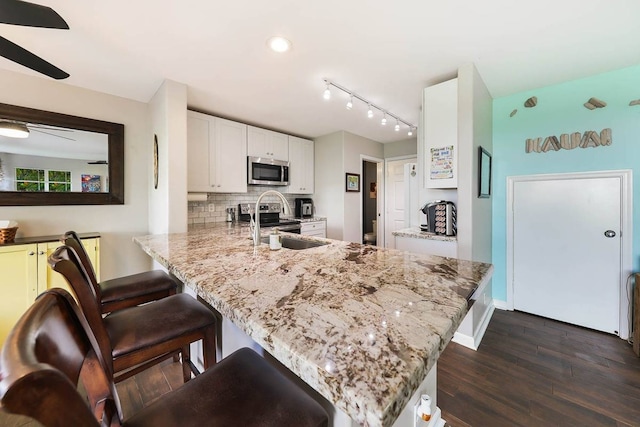 kitchen featuring appliances with stainless steel finishes, tasteful backsplash, ceiling fan, kitchen peninsula, and white cabinets