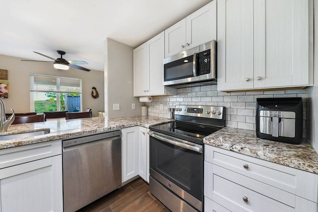 kitchen with white cabinets, backsplash, stainless steel appliances, and ceiling fan