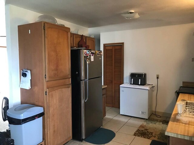 kitchen featuring light tile floors, stainless steel refrigerator, and refrigerator