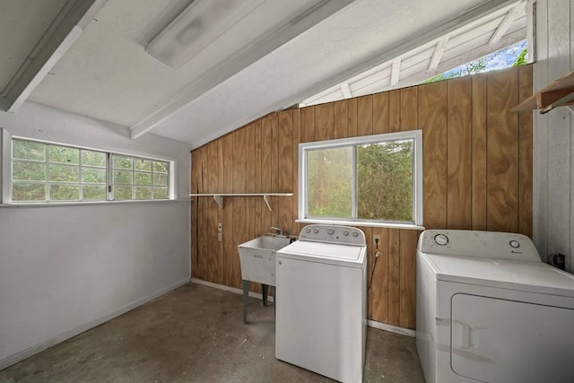 washroom featuring wood walls, sink, and independent washer and dryer