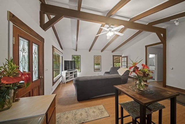 living room with vaulted ceiling with beams, ceiling fan, and light wood-type flooring