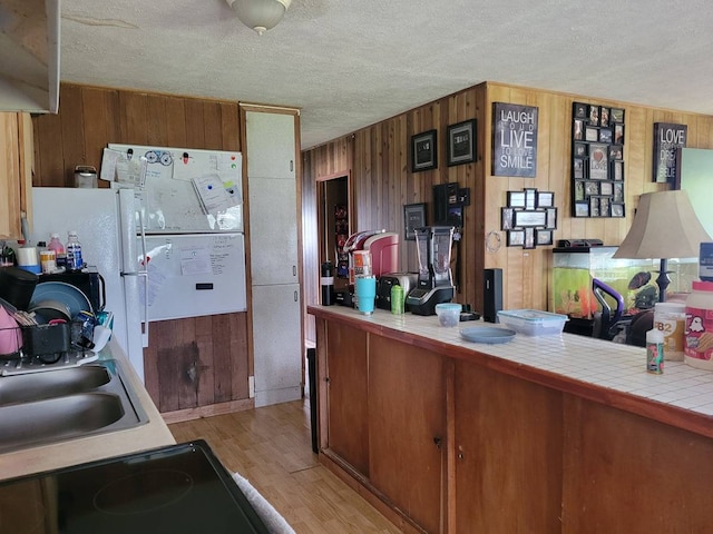 kitchen featuring a textured ceiling, tile countertops, and light wood-type flooring