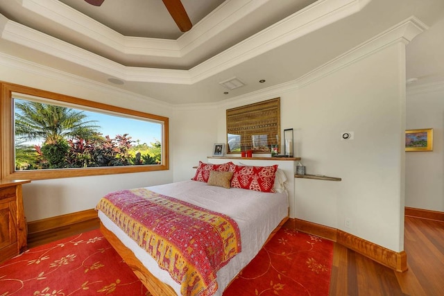 bedroom featuring a tray ceiling, ornamental molding, ceiling fan, and dark hardwood / wood-style flooring