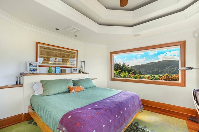 bedroom with crown molding, a raised ceiling, ceiling fan, and hardwood / wood-style flooring