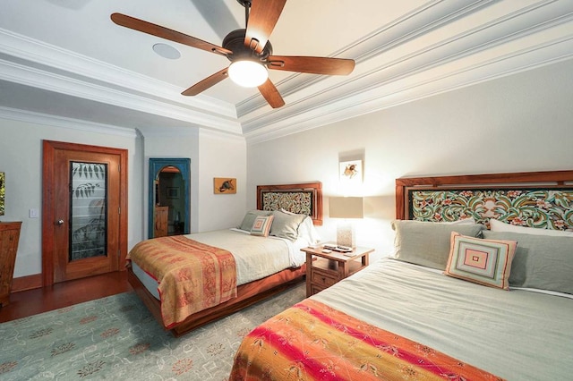 bedroom featuring ceiling fan, crown molding, a raised ceiling, and dark hardwood / wood-style flooring