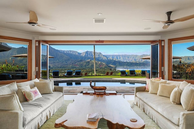 living room with a mountain view, ornamental molding, and ceiling fan