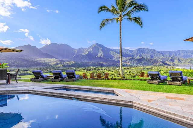 view of swimming pool featuring a lawn, a mountain view, and a patio