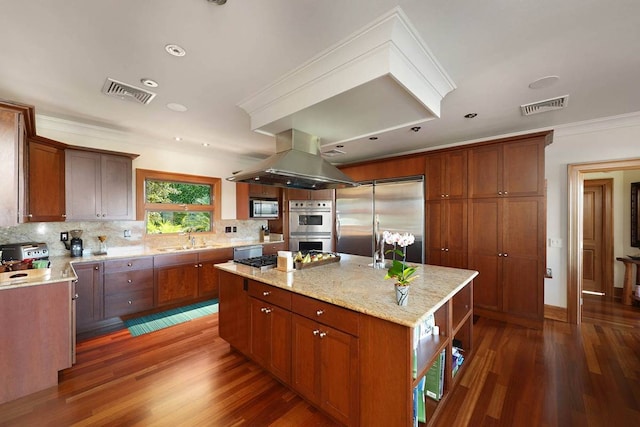 kitchen featuring dark hardwood / wood-style flooring, a kitchen island, built in appliances, island exhaust hood, and light stone countertops