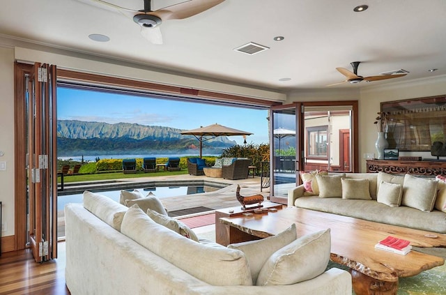 living room with ceiling fan, a water and mountain view, crown molding, and wood-type flooring