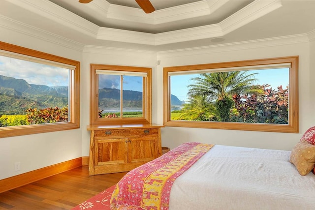 bedroom featuring crown molding, hardwood / wood-style floors, and a raised ceiling