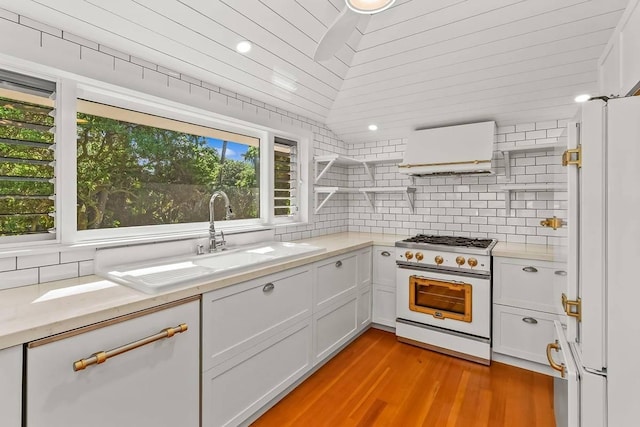 kitchen featuring light wood-type flooring, high end stainless steel range oven, extractor fan, white cabinets, and white fridge